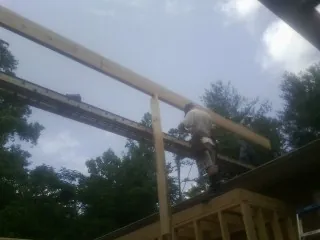 Carpenter setting a ridge beam over a new addition frame — Ice Dam Removal by Roofing Brothers in Guthrie Center