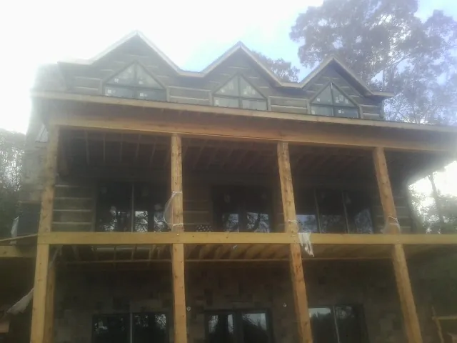 Dormers and porch framing on a large log home under construction — Roof Coating work by our crew in Guthrie Center