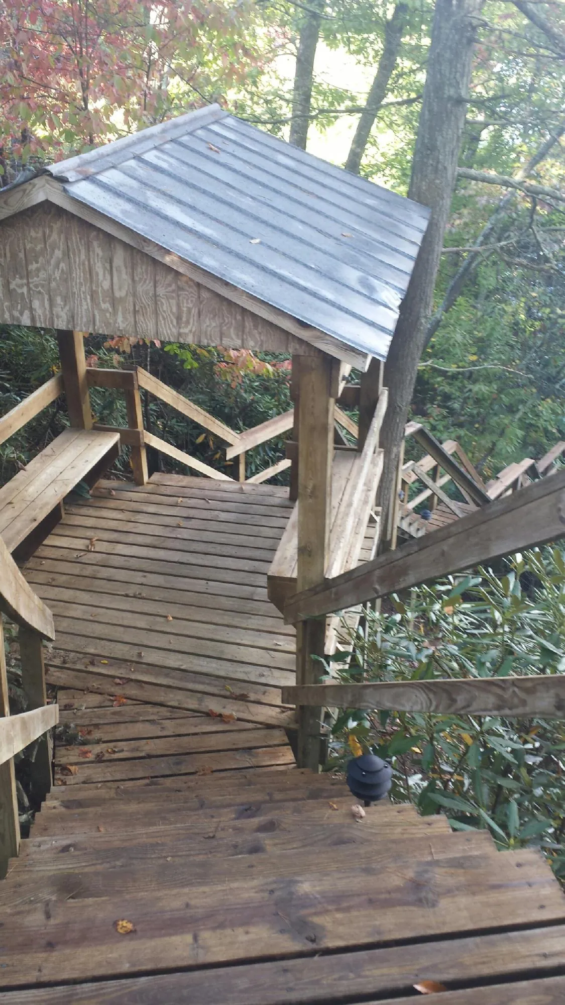 Metal roofed shelter over wooden steps on a wooded walkway — Skylight Repair & Installation work by our crew in Guthrie Center