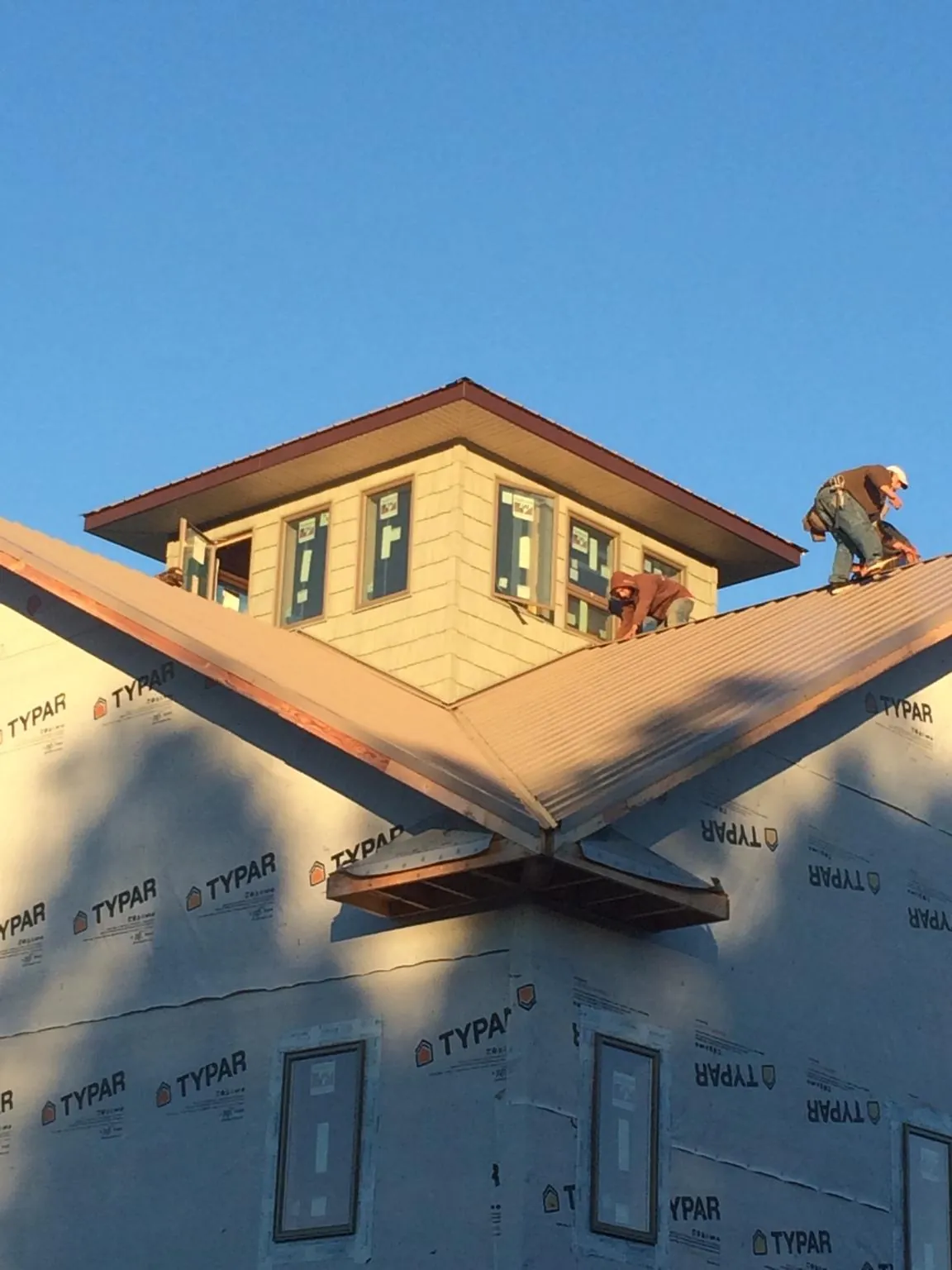 Roofers working around a rooftop cupola on a new metal roof at sunset — Roof Waterproofing in Guthrie Center by Roofing Brothers
